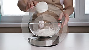 weight for baking recipes, woman weighing flour in a plate on a digital kitchen scales