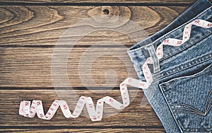 Weight loss concept, Blue jeans and measuring tape on wooden background, Top view with copy space