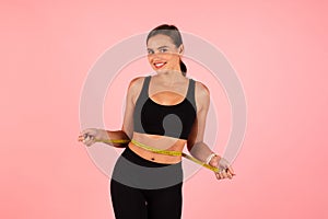 Weight Loss Concept. Sporty Young Woman Measuring Her Waist With Yellow Tape