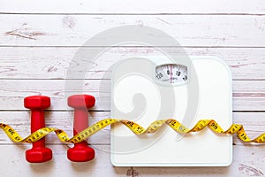 Weight loss control planning. White scale and measuring tape with dumbbell for body dieting healthy life.