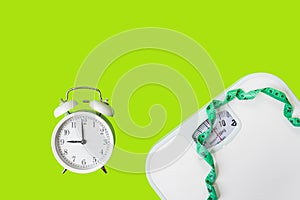 Weight loss control planning. White scale and measuring tape and timing alarm clock for body dieting healthy life.