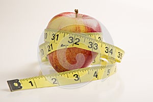 Weight loss solution concept. Red apple with measure tape.