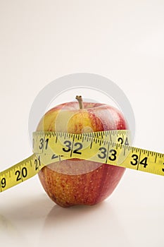 Weight loss solution concept. Red apple with measure tape.