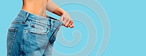 Weight loss. Woman in oversize jeans on blue background