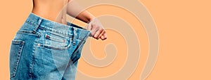 Weight loss. Woman in oversize jeans on pastel background