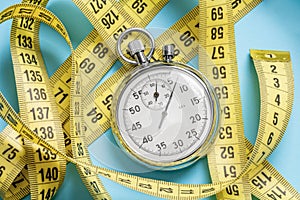 Weight loss workouts. Yellow measuring tape meter and stopwatch on a blue background