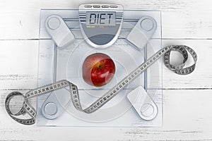 Weight scale with a tailoring meter and a red apple - weight loss