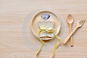 Weight scale with wholesome slice of bread and measuring tape on the wood plate for slimming weight.