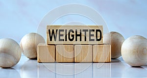 WEIGHTED - word on wooden cubes on a light background with balls
