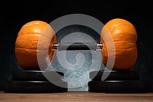 Gym dumbbell barbell with two orange pumpkins as a weight plates.