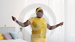 Weightloss. Happy Excited Black Overweight Woman Training With Skipping Rope At Home