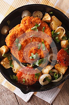 Weiner schnitzel, fried potatoes in a pan closeup. vertical top