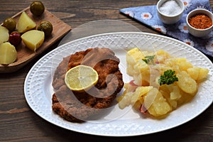 Weiner schnitzel with potato salad on a wooden background