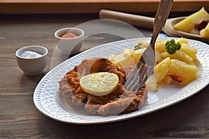 Weiner schnitzel with potato salad on a wooden background