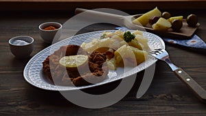 Weiner schnitzel with potato salad on a wooden background