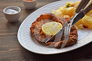 Weiner schnitzel with potato salad on a wooden background