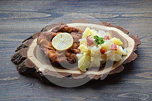 Weiner schnitzel with potato salad on a wooden background