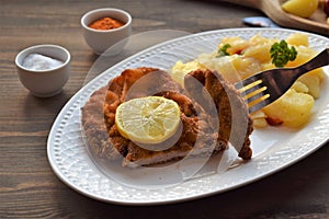 Weiner schnitzel with potato salad on a wooden background