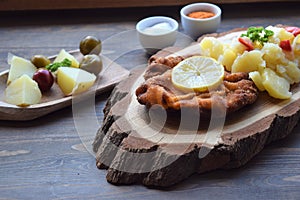 Weiner schnitzel with potato salad on a wooden background