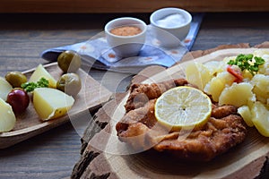 Weiner schnitzel with potato salad on a wooden background