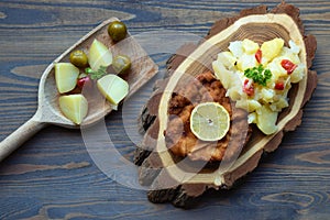 Weiner schnitzel with potato salad on a wooden background