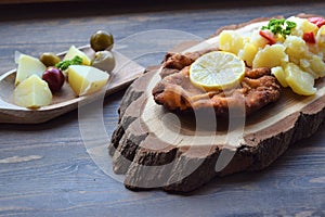 Weiner schnitzel with potato salad on a wooden background