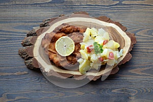 Weiner schnitzel with potato salad on a wooden background