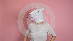 Weird funny video - woman with unicorn head dancing over pink background