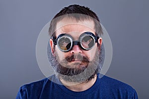 Weird guy with matted hair and large beard wearing broken welding goggles