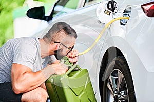 Weird man pumps gasoline from a gas tank into canister