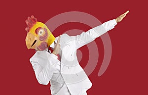 Weirdo man in chicken mask makes movement of famous internet meme about victory on red background.