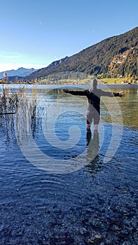 Weissensee - A man standing in the cold lake water with the mountains view