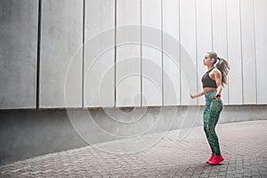 Wel-shaped young woman jumping with rope alone in corridor. She exercises very hard. Model has workout.