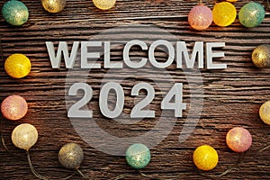 Welcome 2024 alphabet letters decorate with LED cotton balls on wooden background
