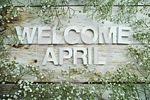 Welcome April alphabet letters with flowers on wooden background