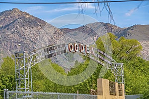 Welcome arch in Ogden Utah against lush trees towering mountain and blue sky photo