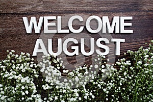 Welcome August alphabet letters with flowers on wooden background