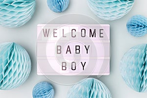 Welcome baby boy. Lightbox with letters and tissue paper balls in a blue color.