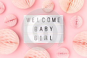 Welcome baby girl. Lightbox with letters and tissue paper balls in a pink color.