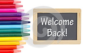 Welcome Back message on a chalkboard with colored watercolor pencils