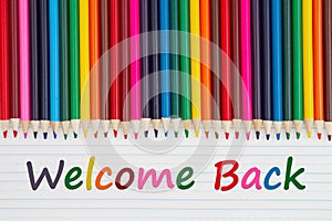 Welcome Back message with color pencils crayons on vintage ruled line notebook paper