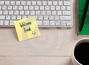 Welcome back message handwritten on a sticky note paper on the office desk