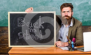 Welcome back. Teacher or school principal welcomes with blackboard inscription back to school. Teacher welcomes new