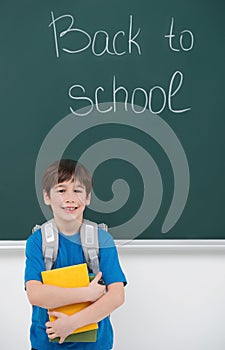 Welcome back to school! Cheerful little schoolboy holding the bo