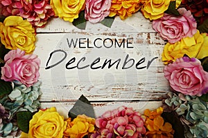 Welcome December text and Flowers Colorful Border Frame on wooden background