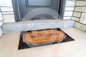 Welcome doormat placed in front of the gray front door of a home entrance