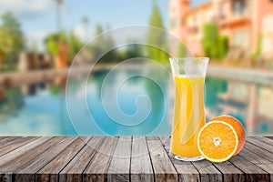 Welcome drink orange juice punch put on wooden table nearly swimming pool with blue water and blue sky in background.