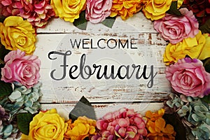 Welcome February text and Flowers Colorful Border Frame on wooden background