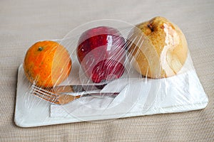 Welcome fruit in hotel room with pear apple and orange put on white bed ready to eat with silver knife and fork