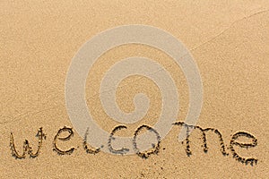 Welcome - hand-written on sandy beach. Travel.